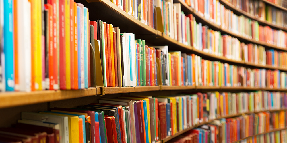 Photo of colorful books on a library shelf.